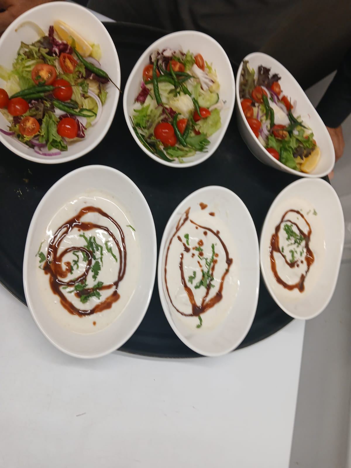 Side salads and raita plated for service